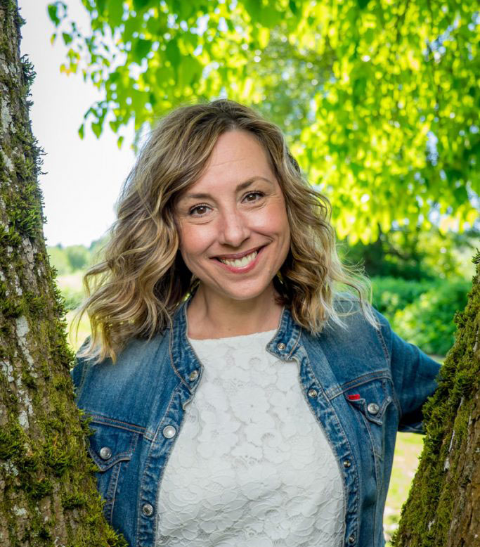 Jenni, founder of Celebrating Loved Ones, smiling outdoors among trees