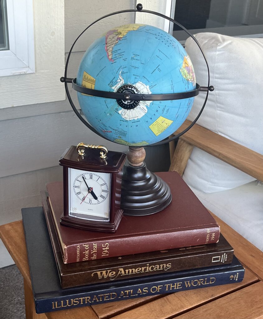 Vintage globe on stacked books with a travel clock — themed décor detail