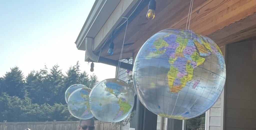 Globe balloons hanging from a patio for a travel-themed birthday celebration