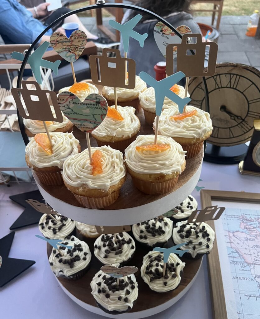 Travel-themed cupcake tower with world-map décor and frosted cupcakes