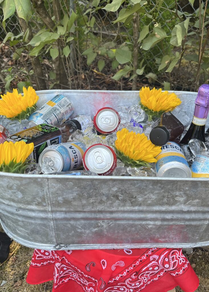 Galvanized tub filled with drinks and sunflowers for an outdoor birthday party