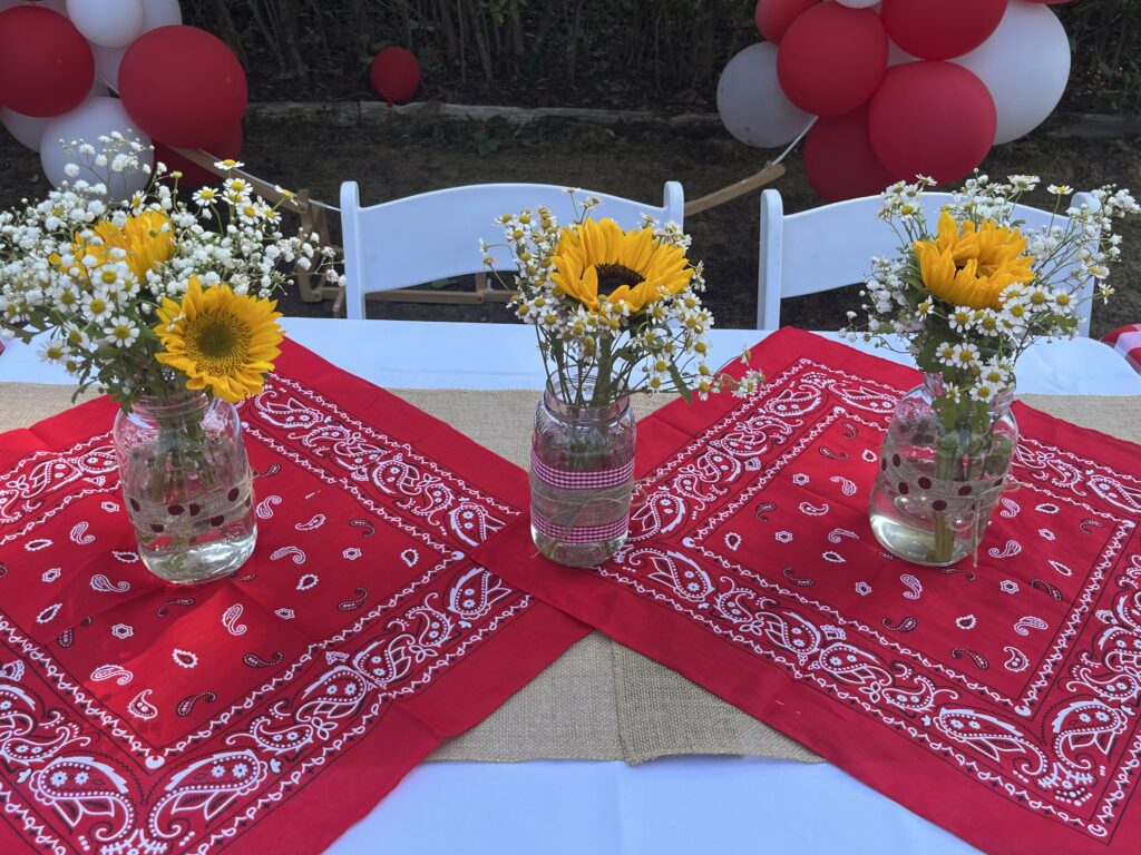 Picnic-style table with red bandana runners and sunflower centrepieces in mason jars