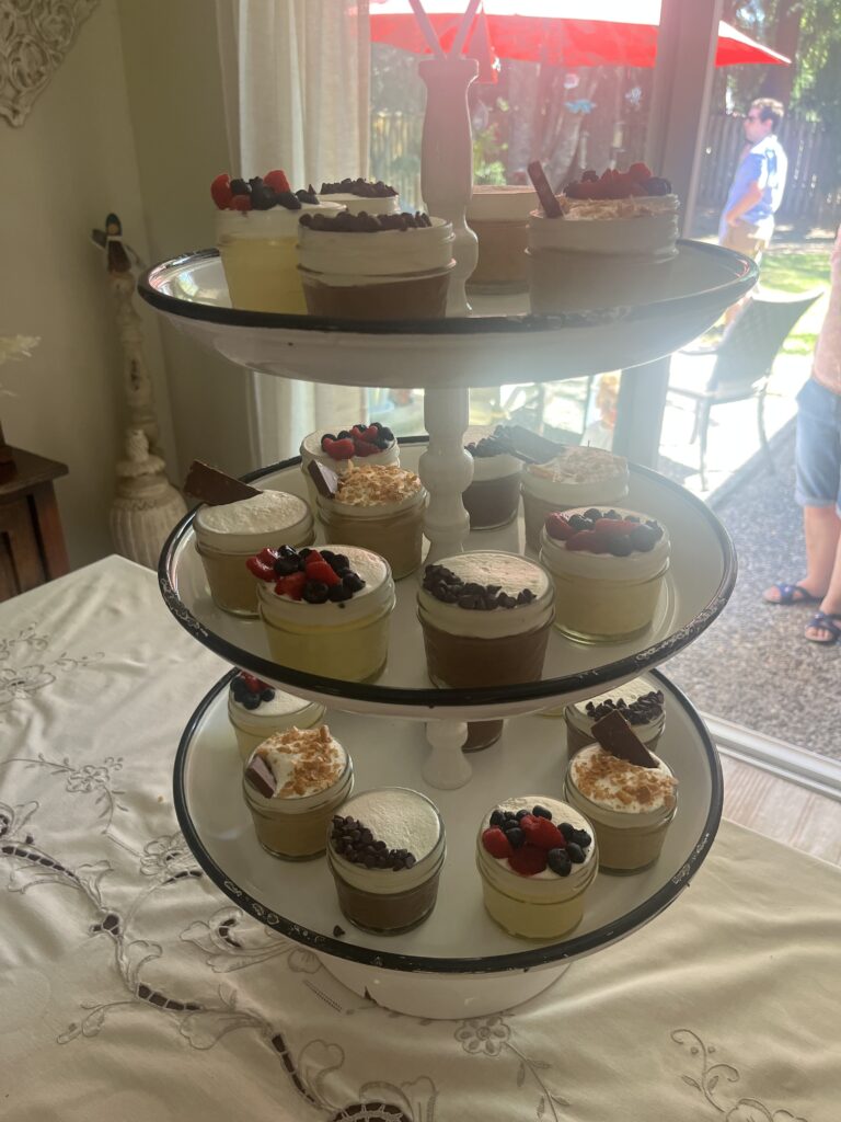 Three-tier dessert stand with jar cakes topped with berries and chocolate