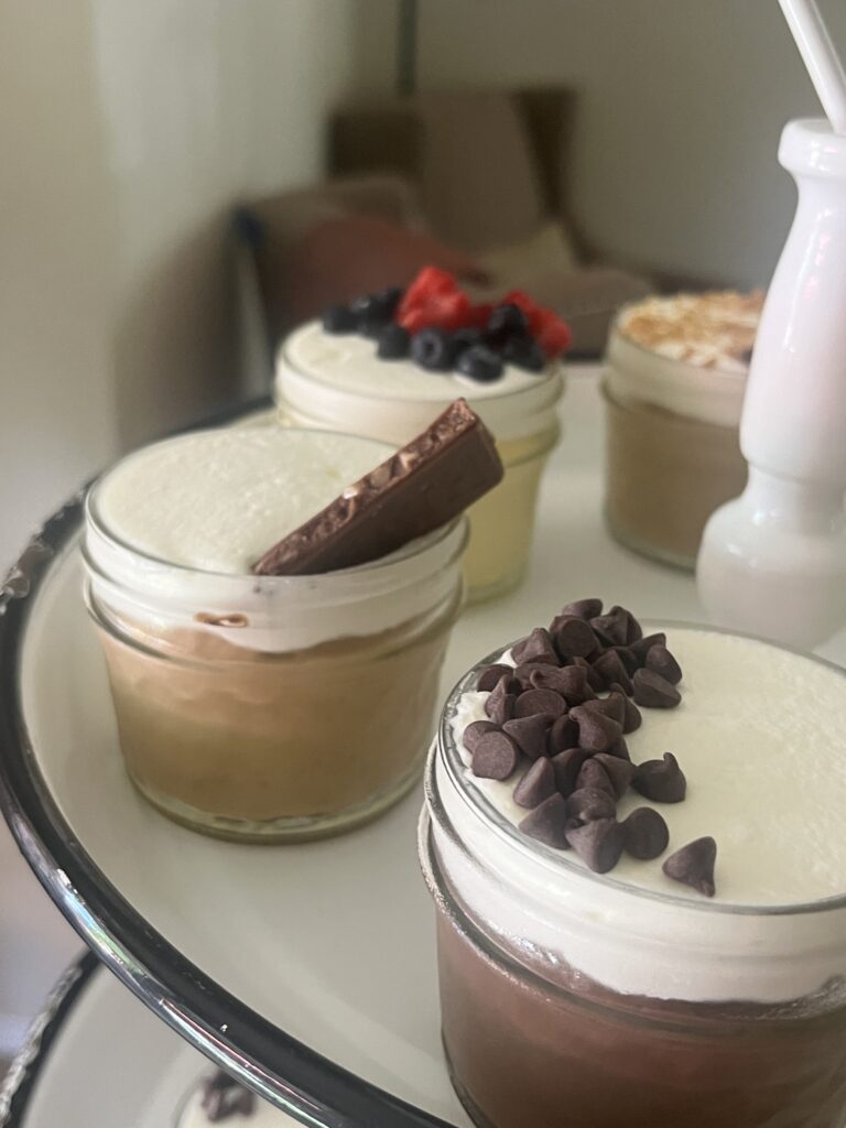 Close-up of individual cheesecake jars topped with whipped cream and chocolate