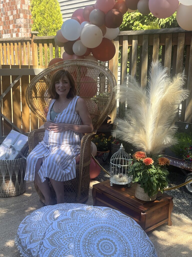 Guest of honour seated in peacock chair surrounded by pampas grass and balloons